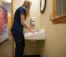 A picture of a women in a blue shirt washing her hands
