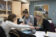 three students take notes and look through microscope during lab