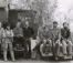 A black and white photo of a group of students sitting on car hoods