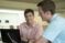 Male student with a computer interacts with another male student