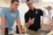 A male student and professor discuss a demonstration in the lab