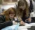 Two female students lean over a tray of samples to analyze them in the lab with a microscope