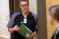 A male student in scrubs speaks with a female student in the simulation lab
