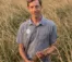 Man standing in field of grain holds onto bunch of it
