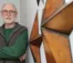 A picture of a man in a green shirt and grey vest standing next to star wall ornaments