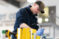 Male student greases a piece of equipment in the high bay in the Agriculture Stewardship Center