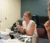 Female student sits at a table and discusses research with others on the research team