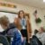 A student teacher stands at the front of class explaining a concept to her students