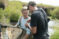 Student in waders in river with net analyzing with another student what was in the net