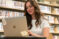 Female student sits in the library on her laptop
