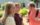 Young blond female in conversation smiling while two males look on outside
