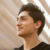 Dark-haired young man with brown eyes looks off into distance with content smile on face