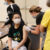 Young man in mask is seated while nurse applies cleanser to his upper arm