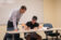 An actuarial science professor leans over to assist a student and review his work