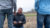 Professor Vos kneels in field talking students about the crop