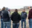 A group of students talk with Professor Vos in a field