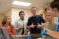 A biology lab group stands around their lab station discussing the lab