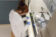 Female student in lab coat examines materials in the chemistry lab