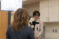 A male wearing headphones films an interview with a camera and light
