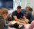A male Dordt student sits among a group of elementary schoolers in class