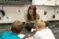 A Dordt student leans over two young students in class as they work on math