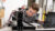 A male student leans over to look at a piece of equipment