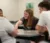 A female student leans over to pick up a card off the table among a group at a table