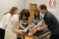 A professor helps two students as they tape another student's ankle