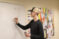 Male student works on math problem on the classroom white board