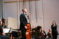 Male cellist stands before the orchestra on stage after completing a solo part