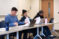 Three students sit at table and listen to class lecture