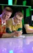 Three young men in rugby shirts lean over counter on stage