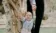 Parents help smiling toddler stand.