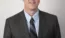 Ross Douma posing for a picture while wearing a suit.