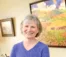 Judy Thompson smiles while holding paintbrushes