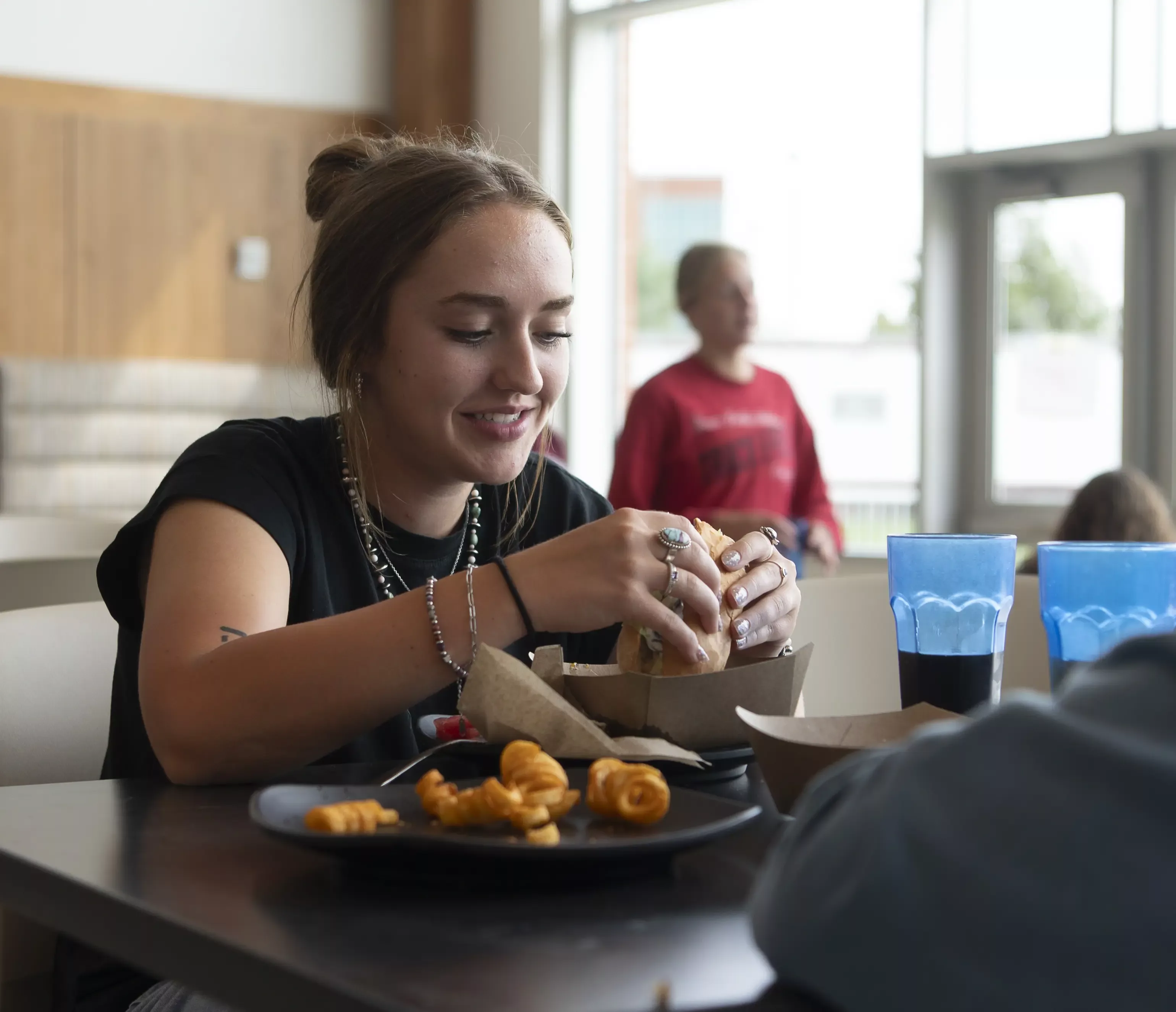 Young woman at table is about to bite into a sandwich