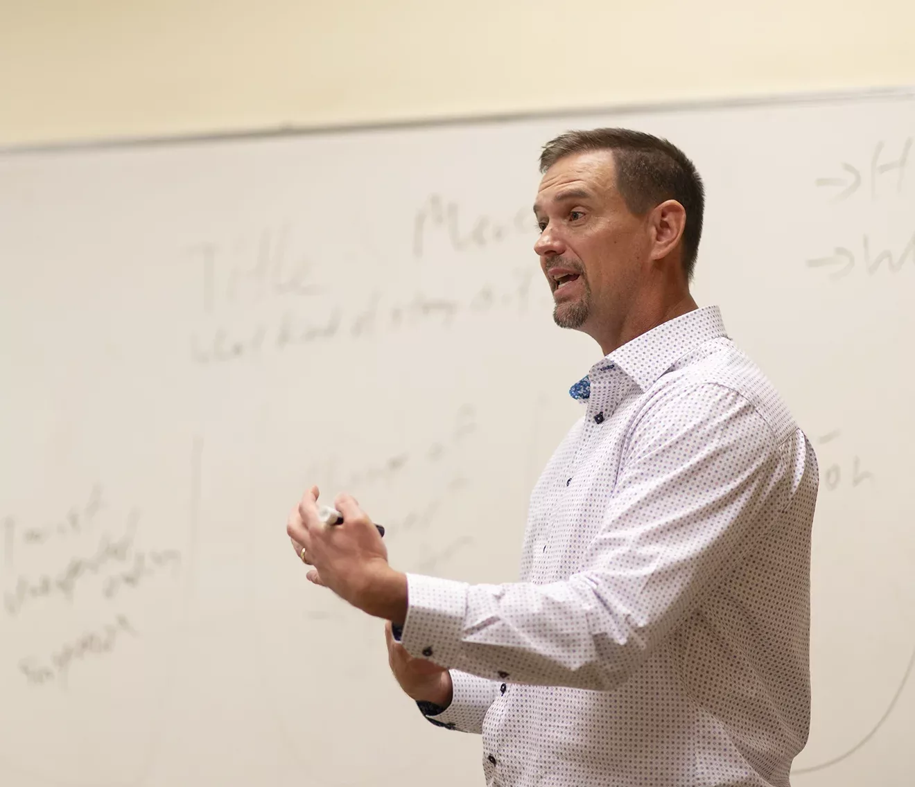 Middle-aged man lectures in front of whiteboard