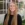 Photo of smiling young lady with long straight hair in front of glass building wearing black shirt