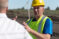 A man in a safety vest and helmet explaining something to another man
