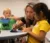 A Teacher helping out two elementary students at a table
