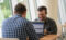 Two men sitting at a table working on their laptops