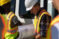 Dordt students in safety vests and helmets look at a construction plan packet
