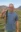 A picture of a man in a grayish-blue shirt holding a fish