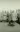 An old photo of a group of men in trench coats, with one digging a hole