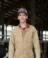 A picture of a man in a brown work jacket with a baseball cap