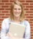 A picture of a women in a light blue shirt with holding a laptop