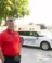 A Midwest Honor Flight organizer stands in front of a vehicle and trailer bearing the Midwest Honor Flight logo