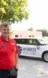 A Midwest Honor Flight organizer stands in front of a vehicle and trailer bearing the Midwest Honor Flight logo