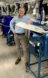 A picture of a man in a light blue shirt standing next to machinery