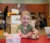 Little blonde girl smiles at camera while sitting at table in preschool room